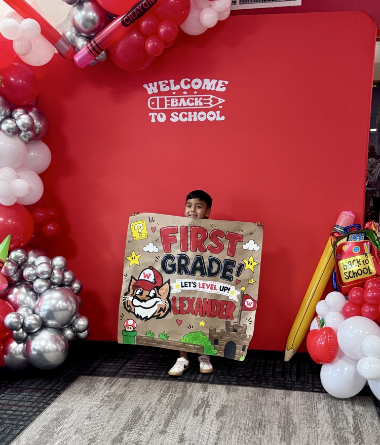 A little student holding a sign that says first grade with Westie 