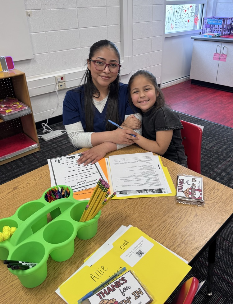 A mom and her daughter sitting in the classroom filing paperwork 