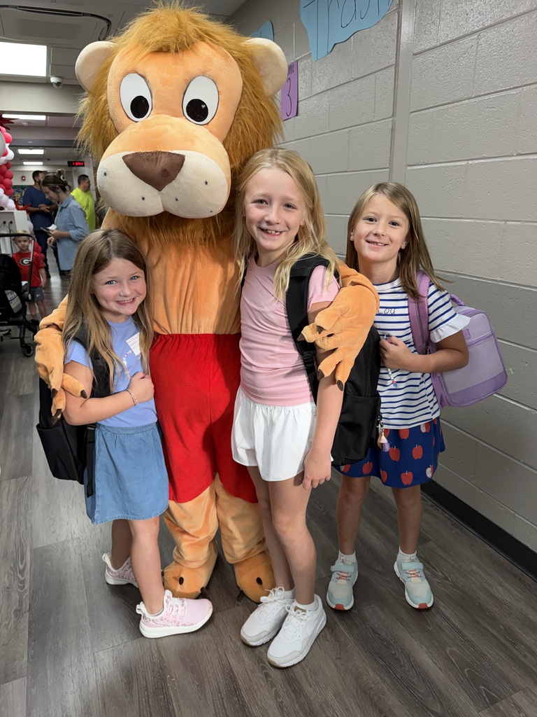 3 students smiling with the brookwood lion mascot