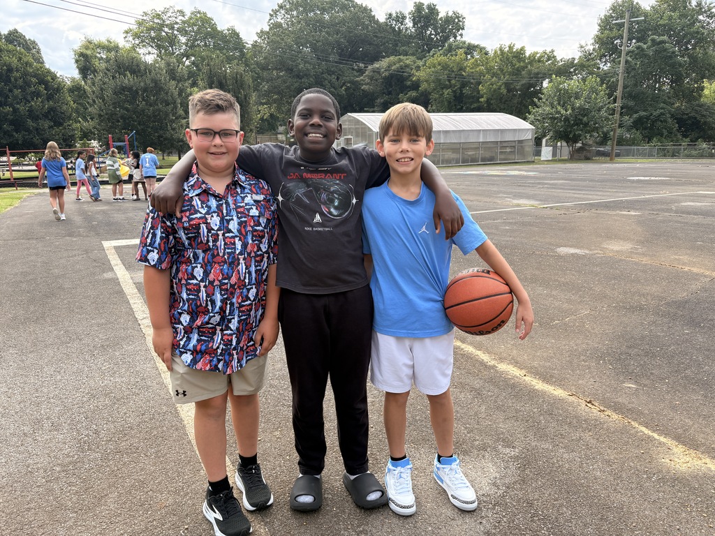three students outside playing basketball at recess
