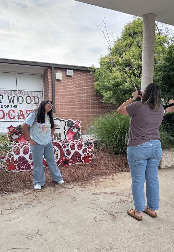 A parent taking a picture of her student in front of the Have a great year yard sign 