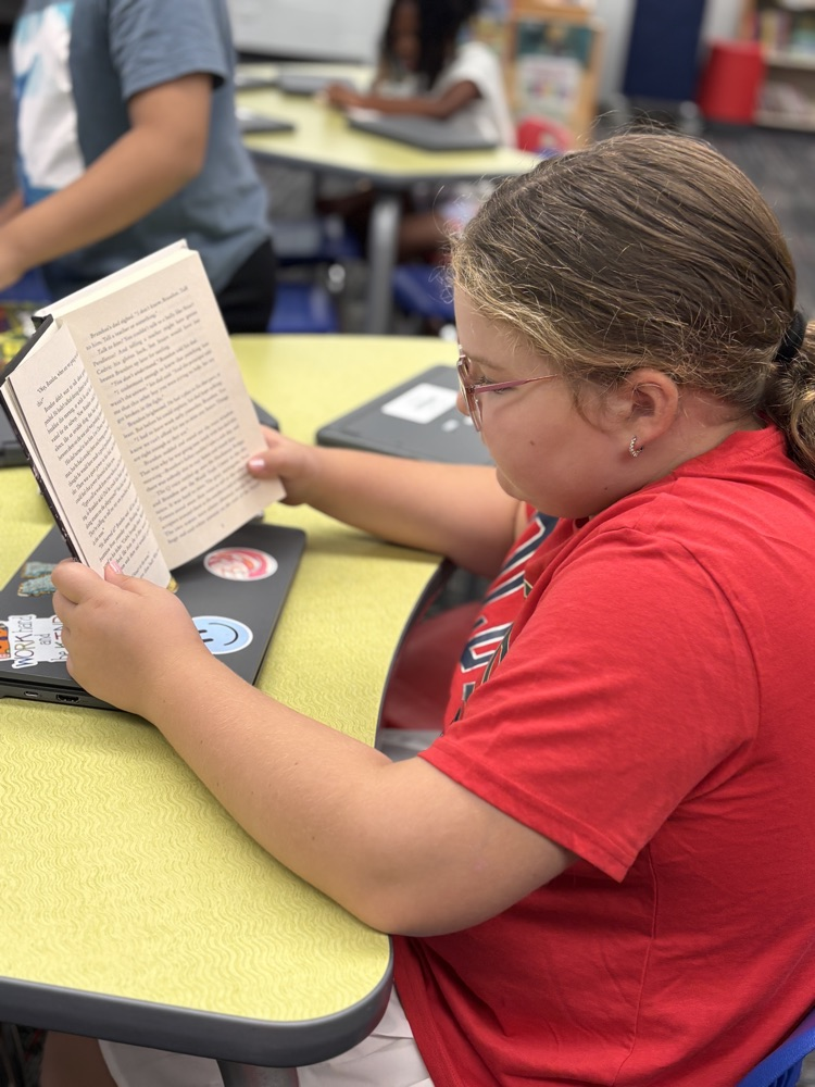 A student seating in the media center reading a book