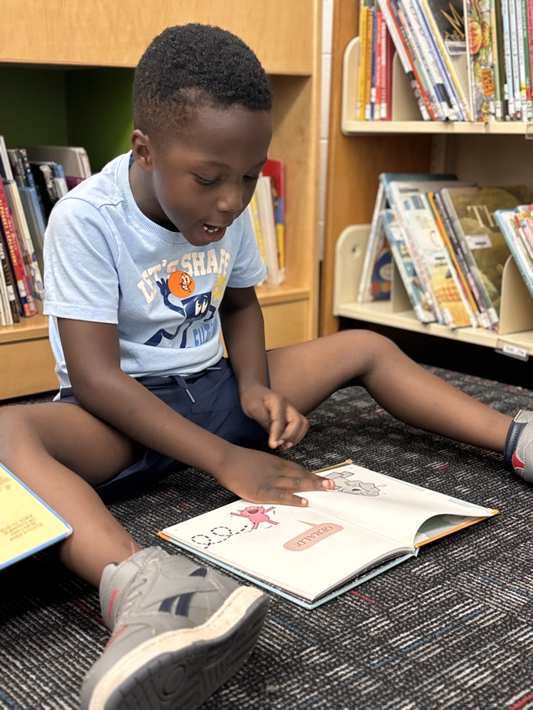 A student seating in the media center reading a book
