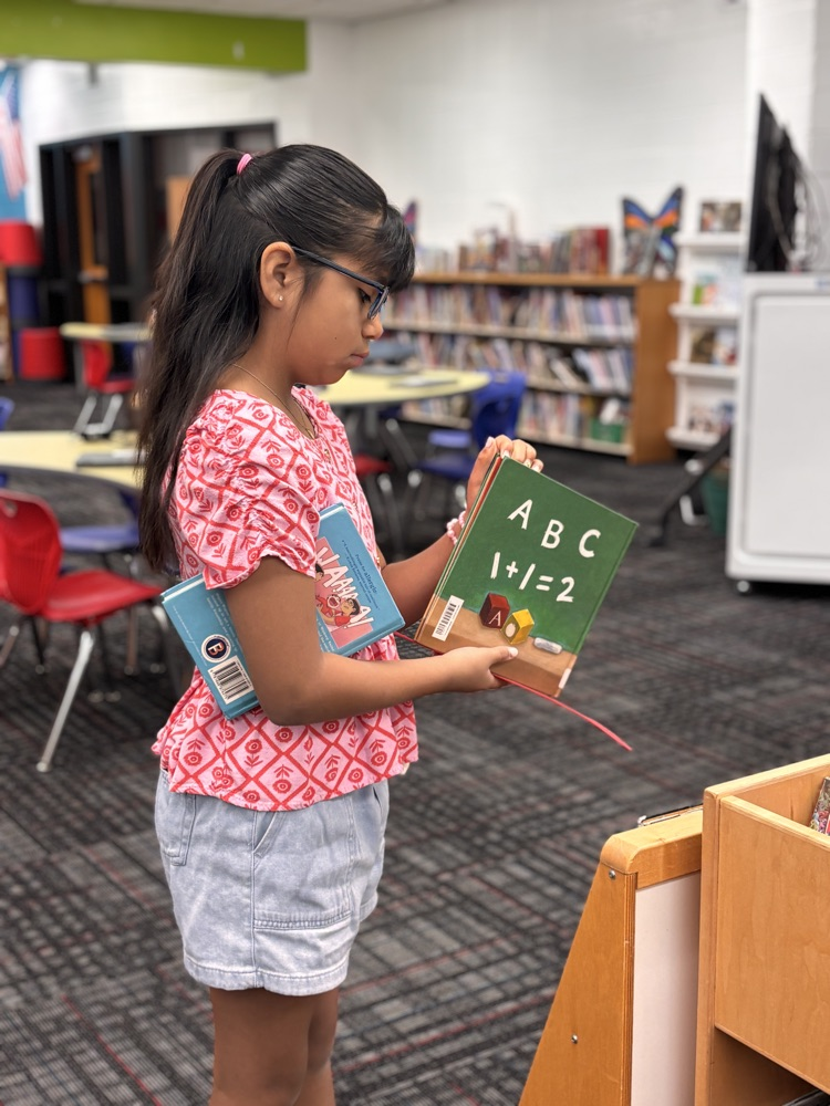 Student holding a book while looking at another book