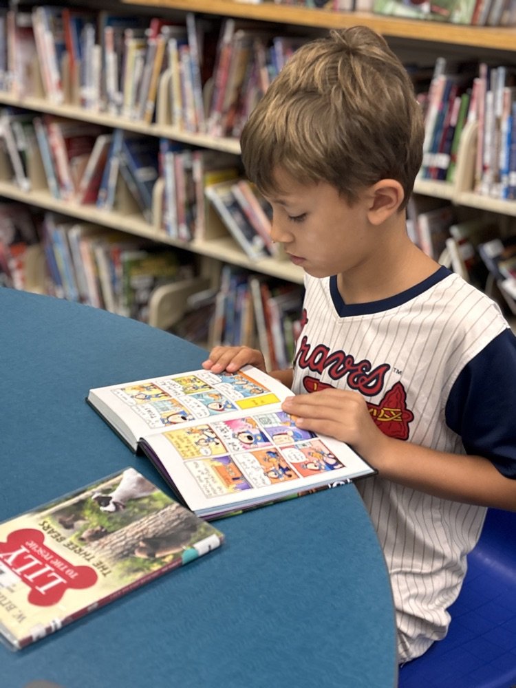 Student seating at the media center reading a graphic novel