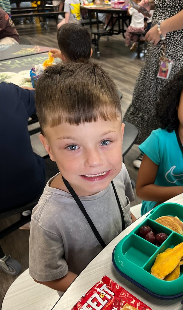 student smiling at lunch with an open lunch box
