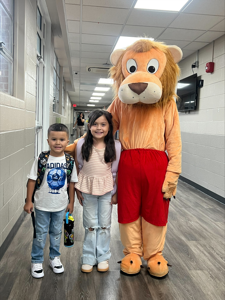 two students posing with our Lion mascot