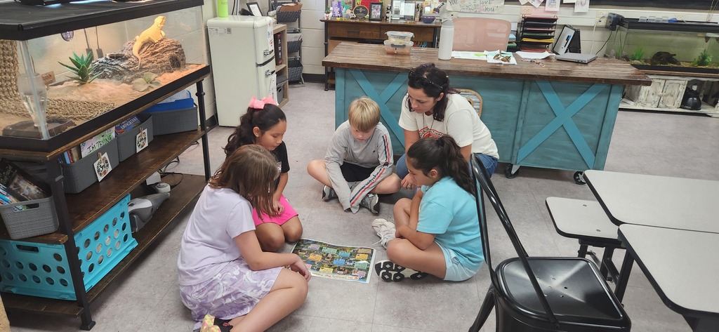 students gathered around a map to learn about hunger in different parts of the world