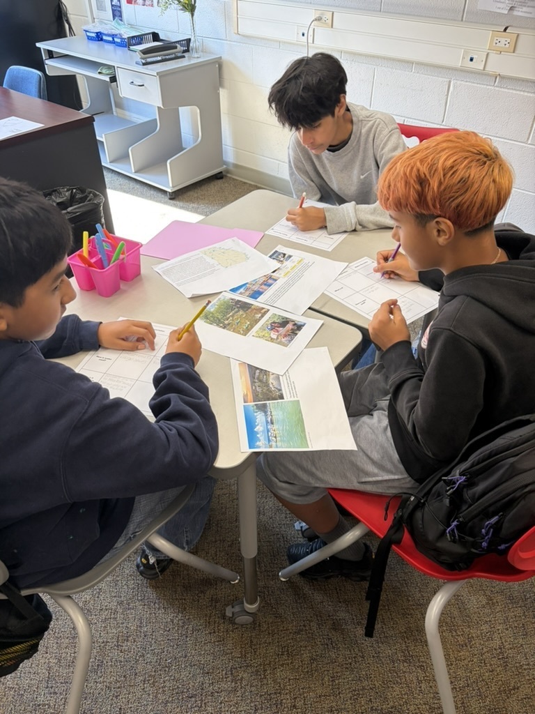 3 students sitting at desks working on a Georgia Studies assignment
