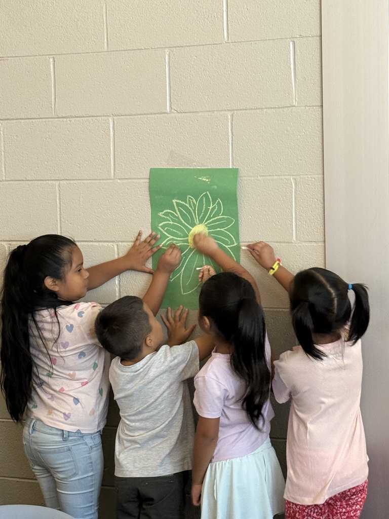 students in the media center touching a picture of a flower as they pretend to be pollinators going from flower to flower spreading pollen