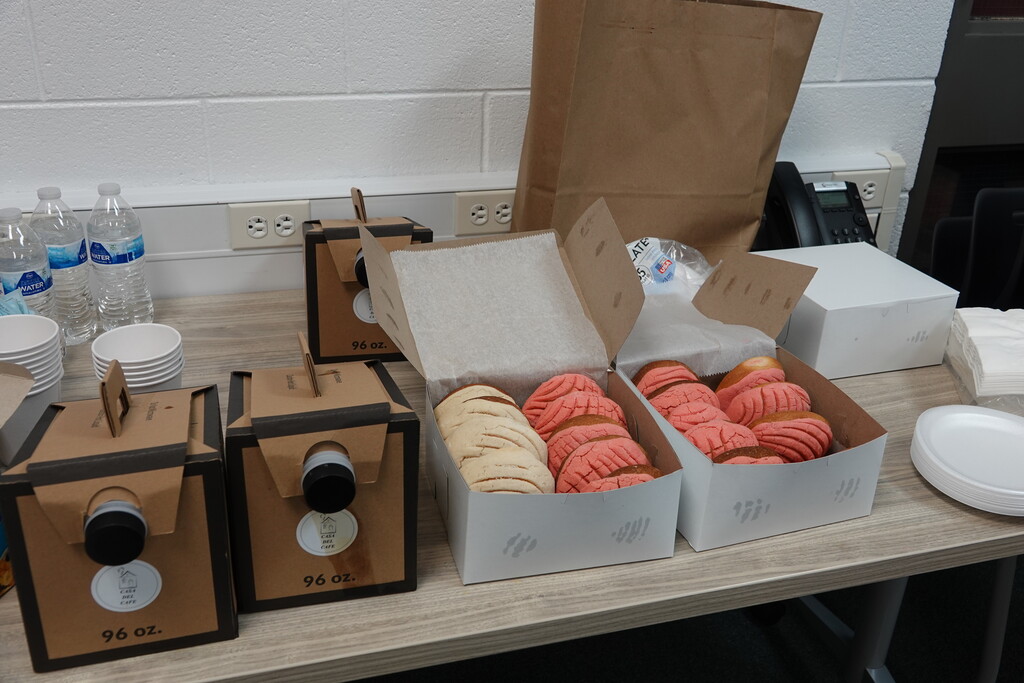 Refreshment table setup featuring boxes of Mexican sweet bread and coffee boxes.