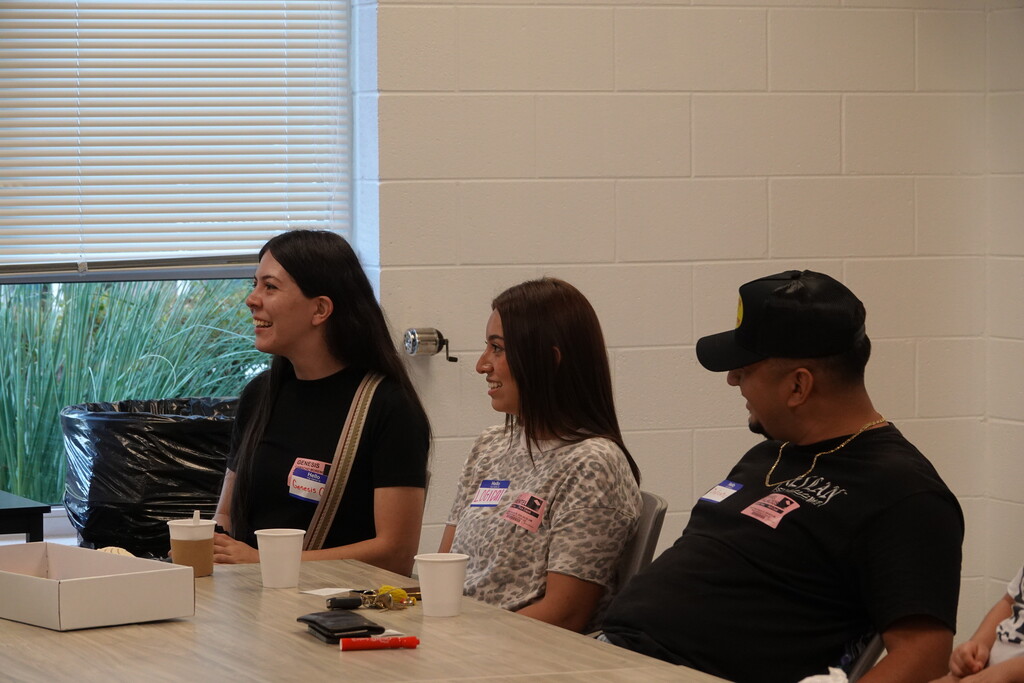 Meeting attendees seated at a table listening and smiling.