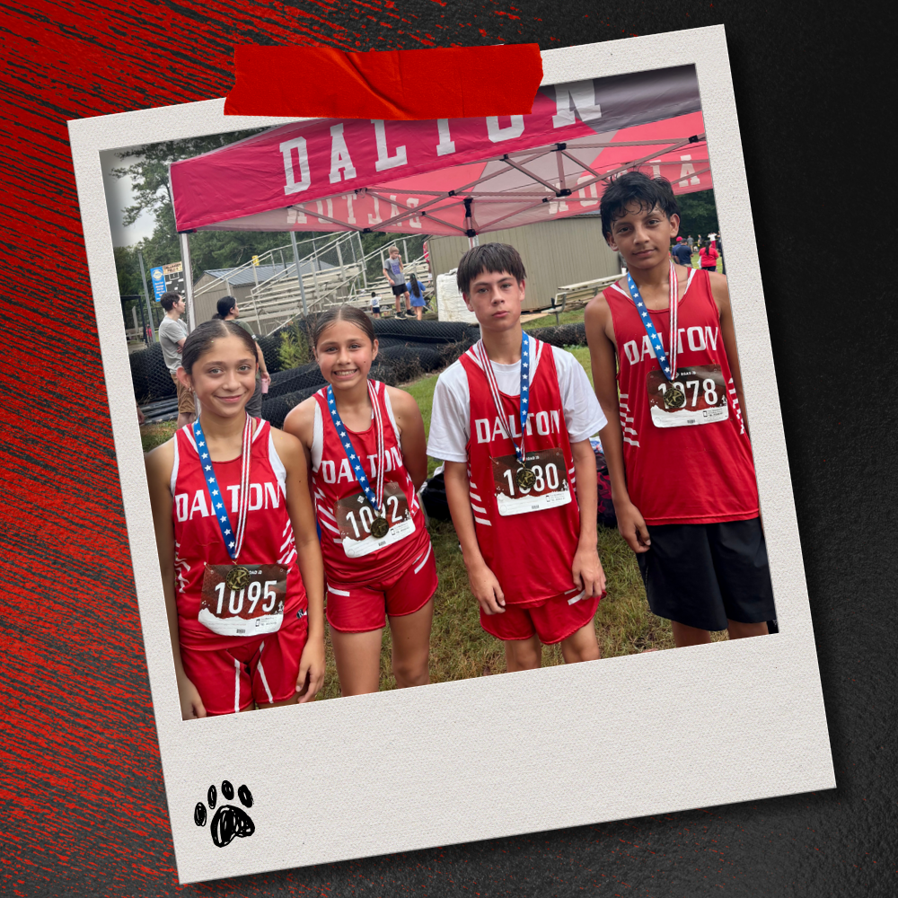 Four Dalton Middle cross country runners in red uniforms stand beneath a Dalton team tent after the race, each wearing a medal. The photo is displayed in a taped Polaroid-style frame on a textured red-and-black background with a paw print accent.