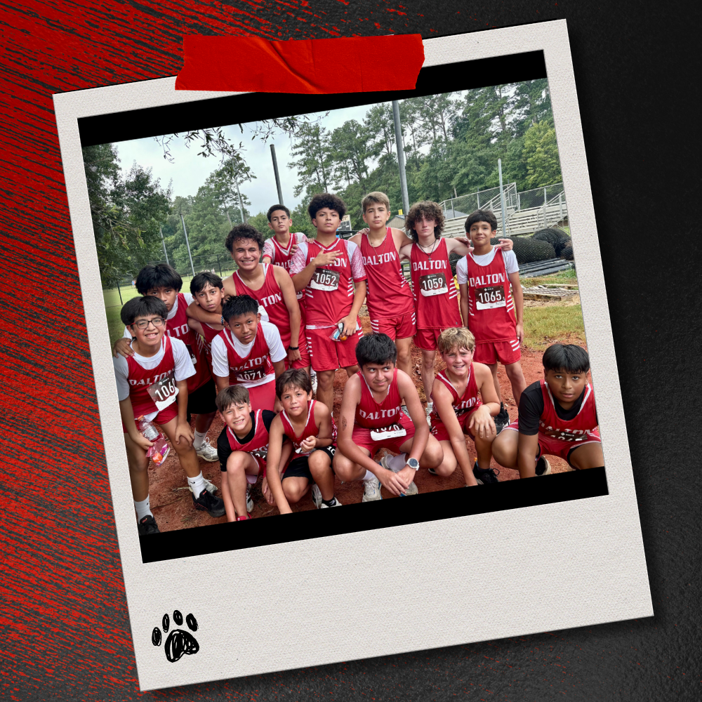 A large group of Dalton Middle boys cross country runners in red uniforms gather for a team photo after competing. The photo is displayed in a taped Polaroid-style frame on a textured red-and-black background with a paw print accent.