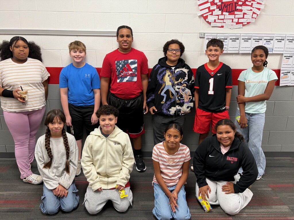 Group photo of ten students gathered in a school hallway as part of the Jedi team's weekly recognition celebration. Students are standing together holding candy and recognition items. The group includes the two Jedi of the Week students and highlights the team's Culturize theme, "Carry the Banner."