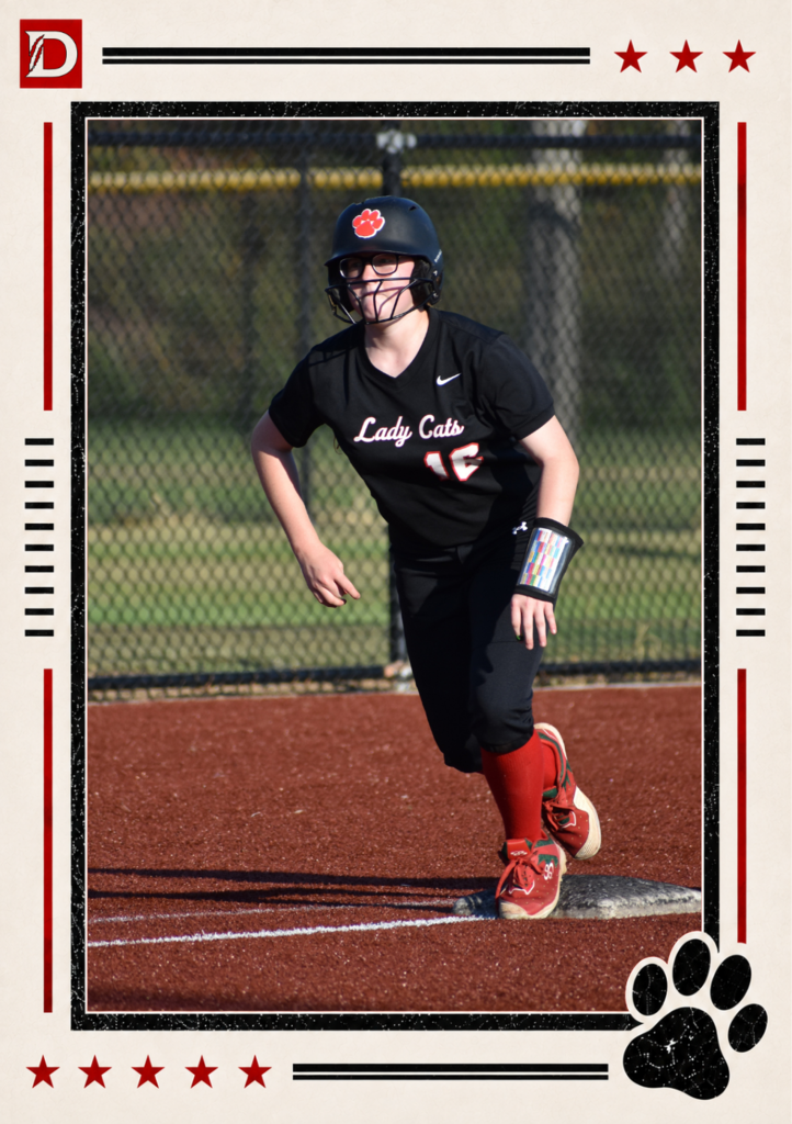 Newspaper-style Dalton Middle Athletics action photo showing a Varsity Lady Cats softball player, #16, running the bases. She wears a black uniform, red socks, and a black helmet with a red paw logo and is pictured stepping off a base while looking toward the field. The photo is framed with red stars, black lines, the Dalton D logo, and a black paw print.