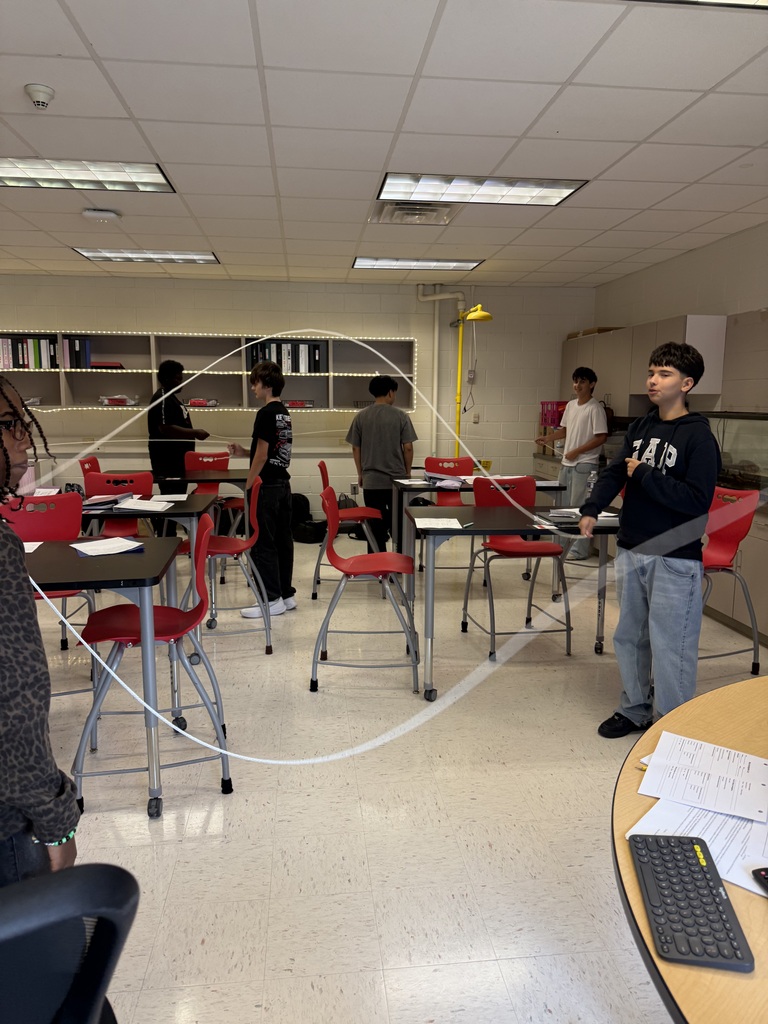 Students in a science classroom making waves using a rope.