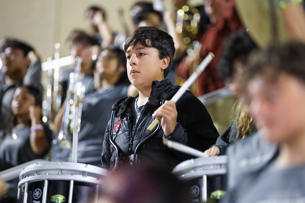 A marching band percussionist playing drums during a football game.