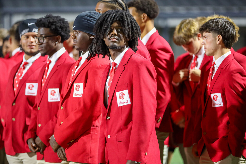 Dalton High School football players in red blazers lined up on the sideline.