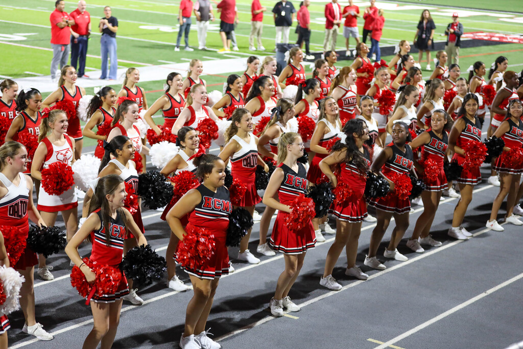 Cheerleaders performing a synchronized routine on the track during a football game.