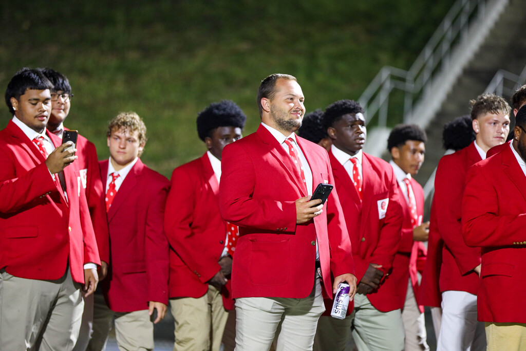 Dalton High School football players wearing red blazers standing together on the sidelines.