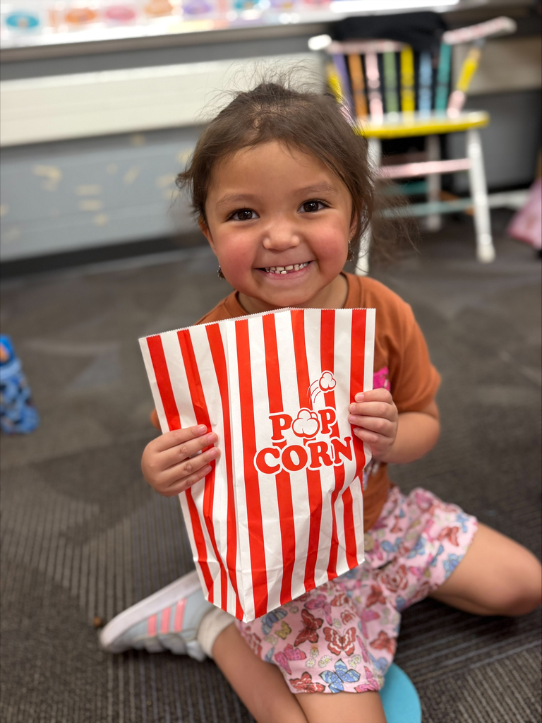student smiling with a red striped bag that says popcorn during a lesson about their 5 senses