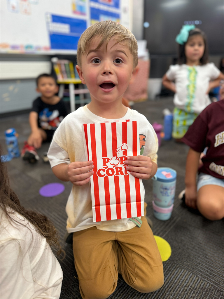 student smiling with a red striped bag that says popcorn during a lesson about their 5 senses