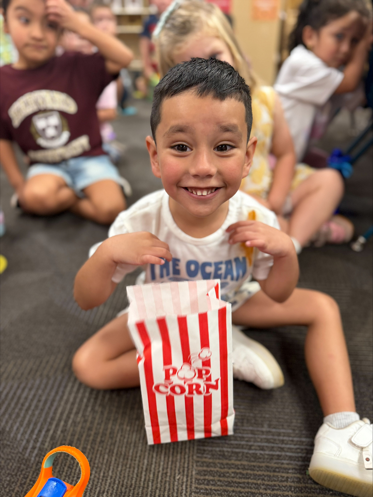 student smiling with a red striped bag that says popcorn during a lesson about their 5 senses