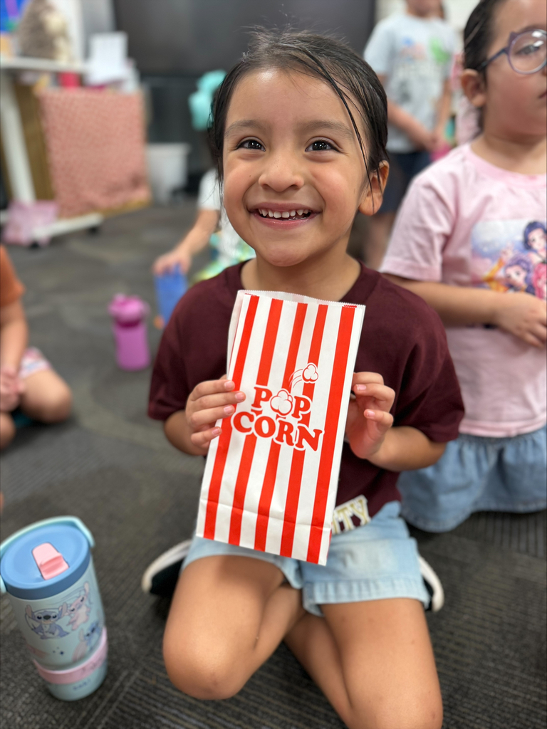 student smiling with a red striped bag that says popcorn during a lesson about their 5 senses