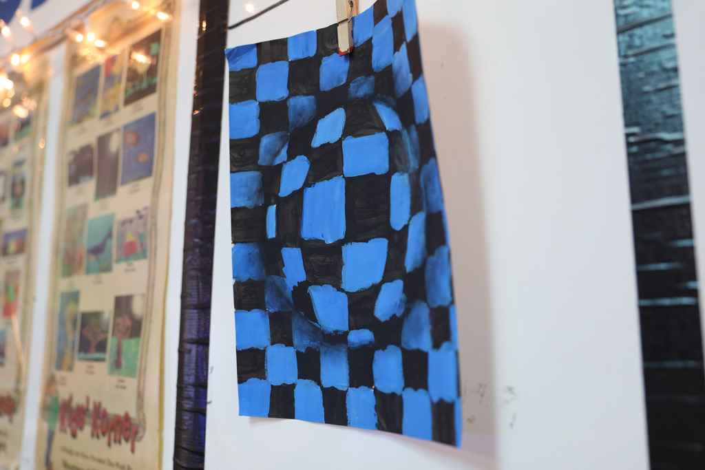 A finished student artwork displaying an optical illusion checkered pattern in blue and black.