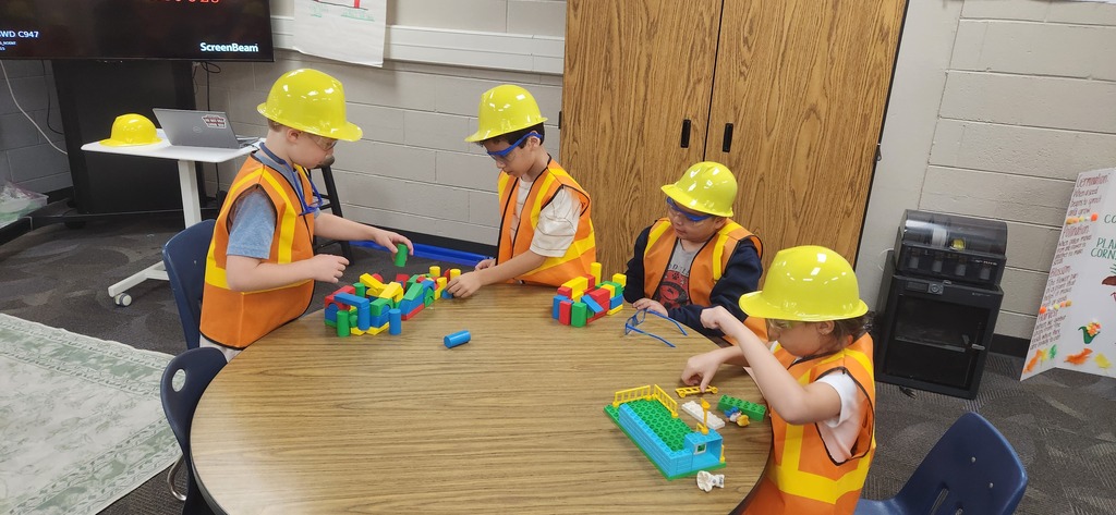 students smiling at a table in a classroom while using blocks and magnet tiles to experience a day on the job of a construction worker!