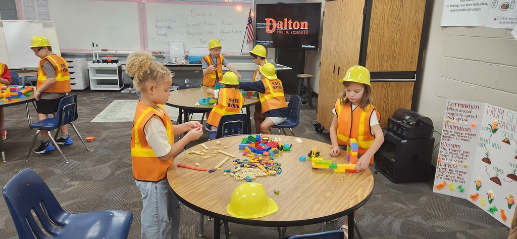 students smiling at a table in a classroom while using blocks and magnet tiles to experience a day on the job of a construction worker!