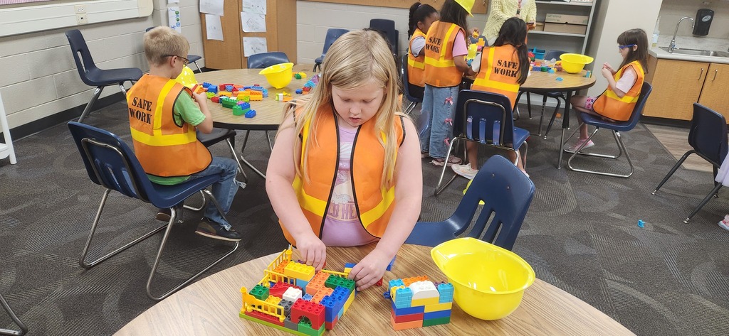 students smiling at a table in a classroom while using blocks and magnet tiles to experience a day on the job of a construction worker!