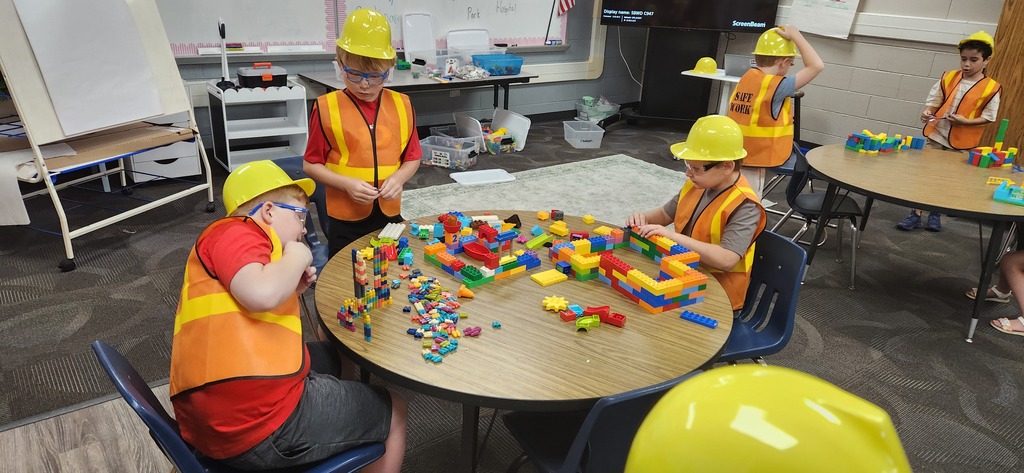 students smiling at a table in a classroom while using blocks and magnet tiles to experience a day on the job of a construction worker!