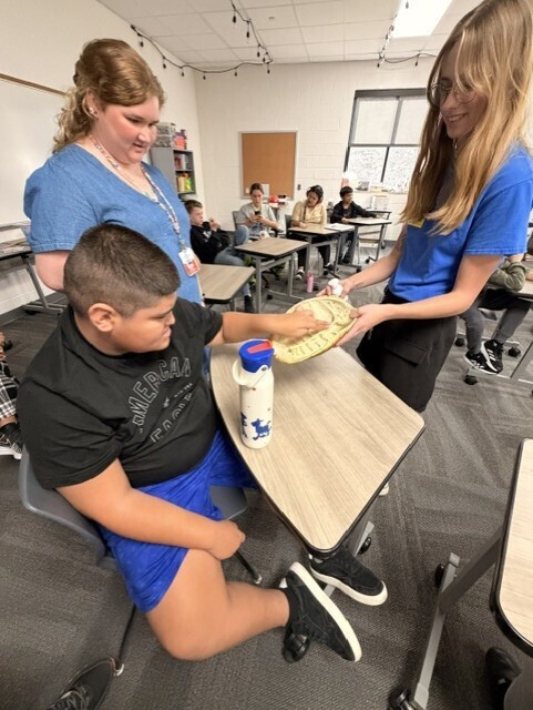 Student participates in a hands-on learning activity by interacting with a small reptile during a Tennessee Aquarium presentation in science class. The visit allowed students to make real-world connections to science concepts.