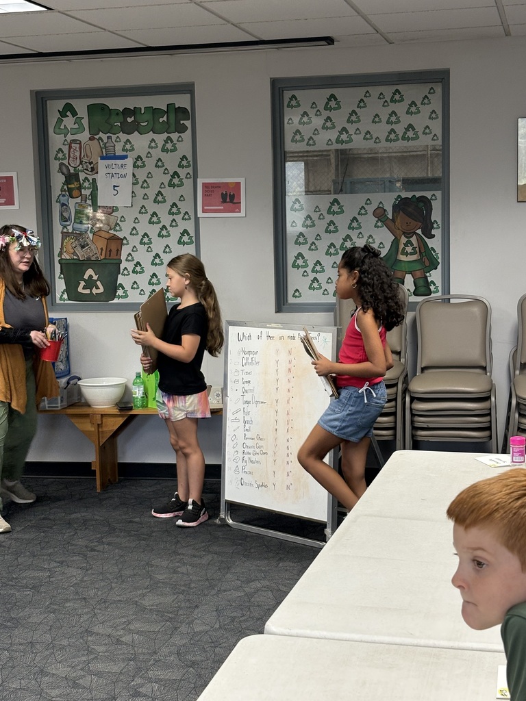 students sharing what they learned while touring the recycling facility. There are two students standing in front of a chart paper talking to the class and the teacher
