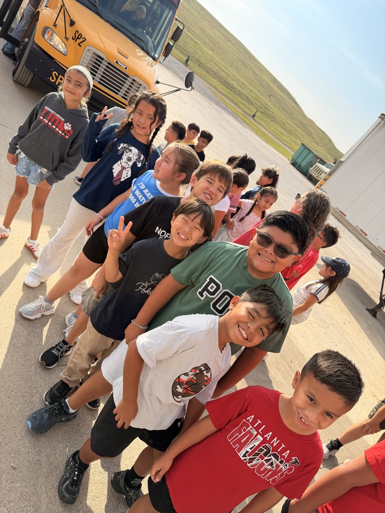 students standing outside of a bus on a pretty day smiling for the camera as they wait to begin their field trip to the landfill