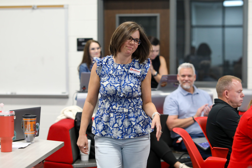A female staff member walking up to receive an award as colleagues applaud.