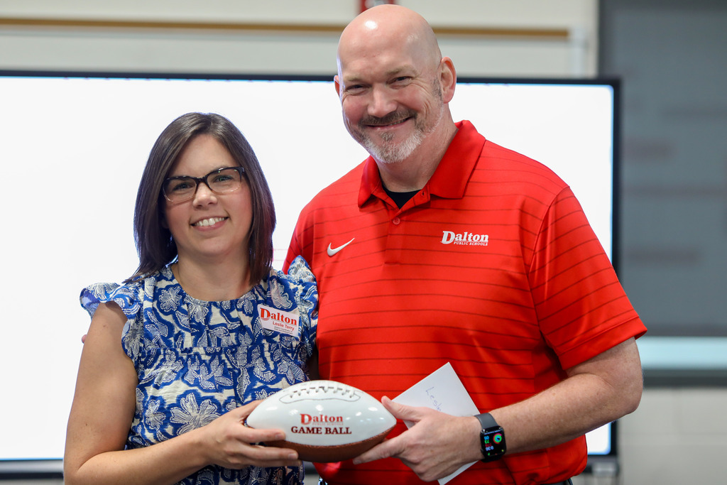 Dr. Steven Craft posing with a female Game Ball award winner holding her trophy football.