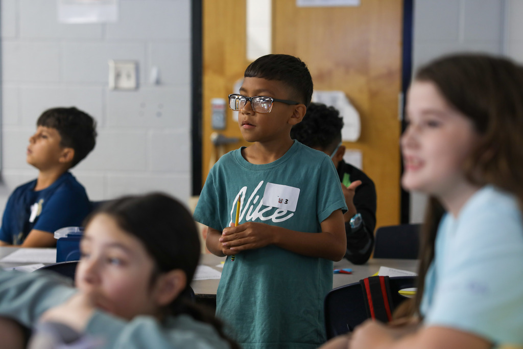 Students standing up and smiling during an interactive group activity in a classroom.