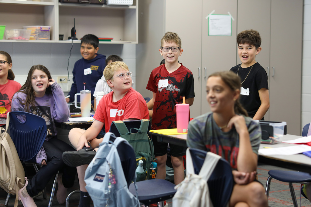 Students standing up and smiling during an interactive group activity in a classroom.