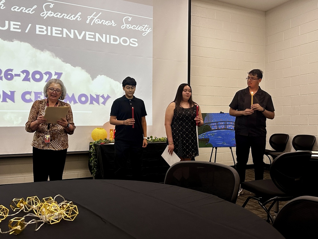 Alt Text: Group photograph of newly inducted French and Spanish Honor Society members holding certificates and candles in front of an Adidas logo backdrop.
