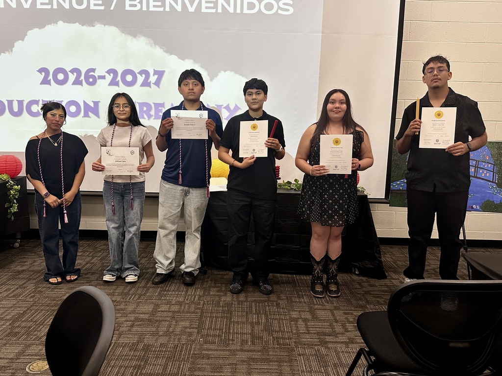 Alt Text: Group photograph of newly inducted French and Spanish Honor Society members holding certificates and candles in front of an Adidas logo backdrop.