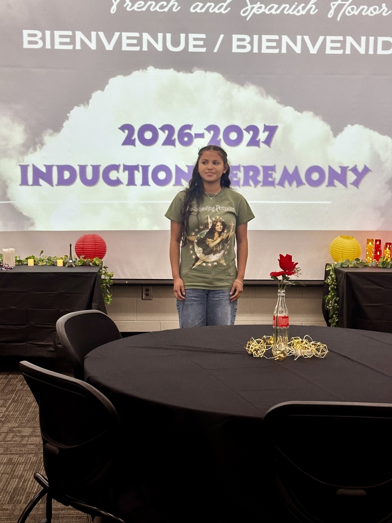 Alt Text: Group photograph of newly inducted French and Spanish Honor Society members holding certificates and candles in front of an Adidas logo backdrop.