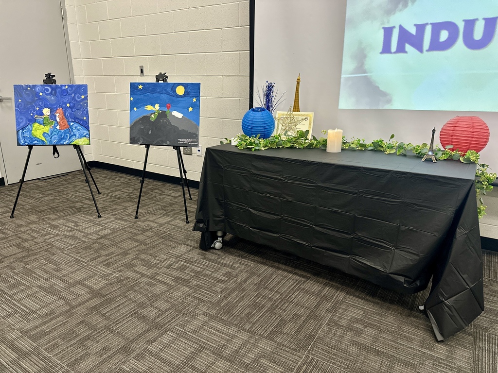 Alt Text: Group photograph of newly inducted French and Spanish Honor Society members holding certificates and candles in front of an Adidas logo backdrop.
