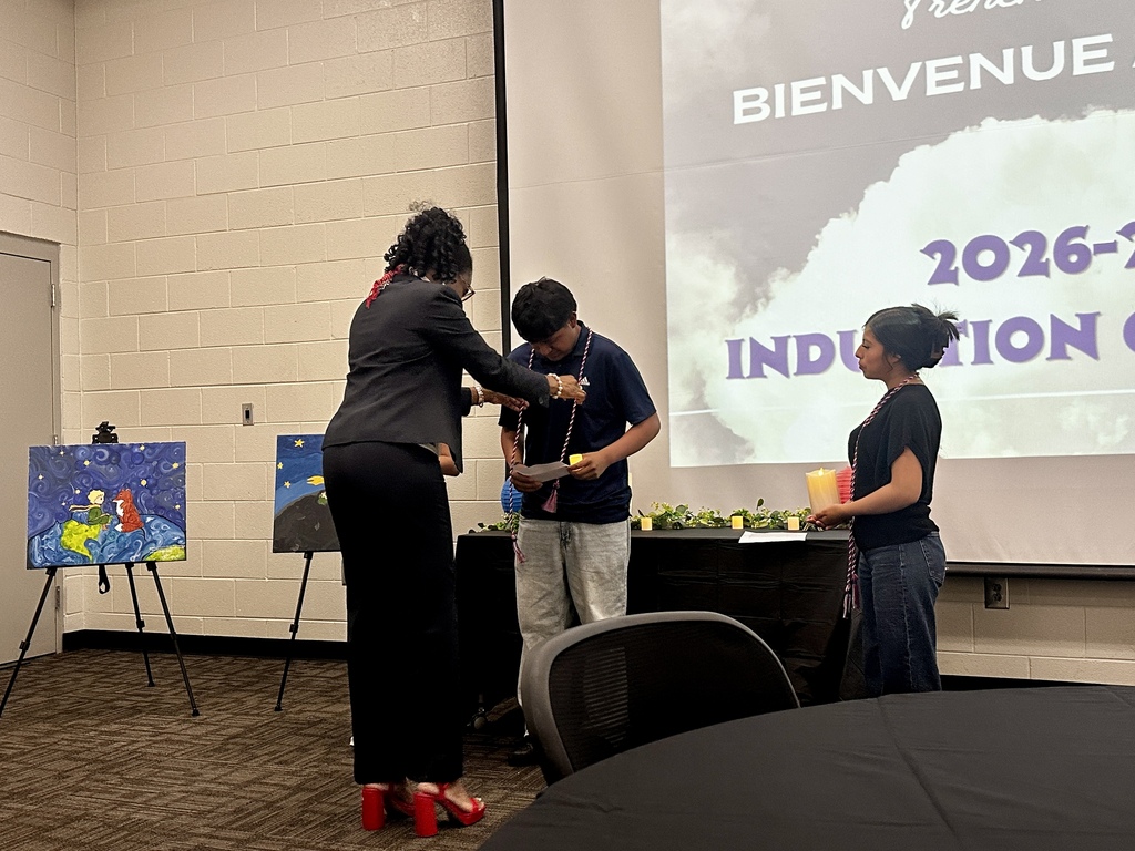 Alt Text: Group photograph of newly inducted French and Spanish Honor Society members holding certificates and candles in front of an Adidas logo backdrop.