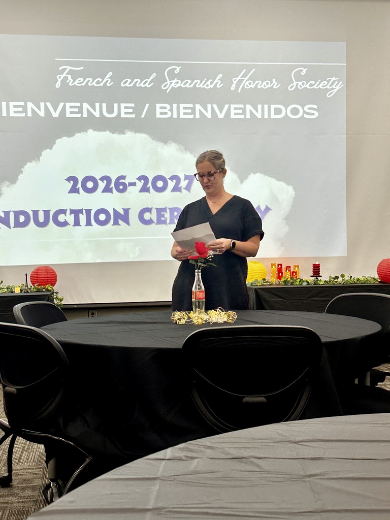 Alt Text: Group photograph of newly inducted French and Spanish Honor Society members holding certificates and candles in front of an Adidas logo backdrop.