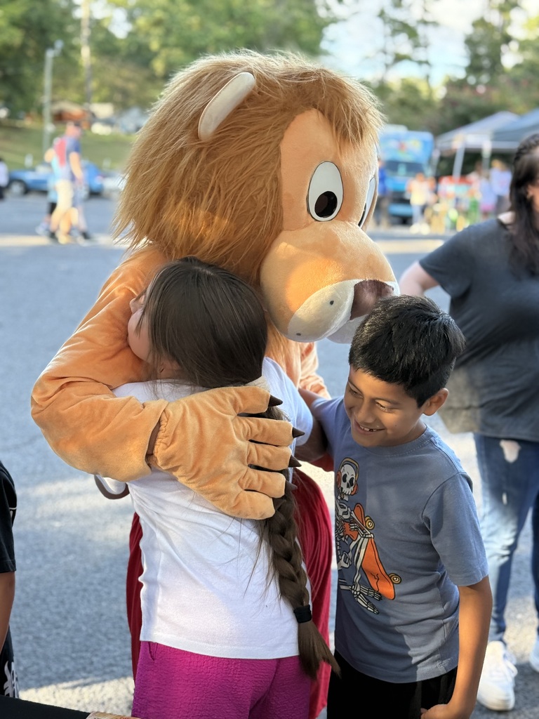 2 students hugging the Brookwood Lion mascot at Literacy Night