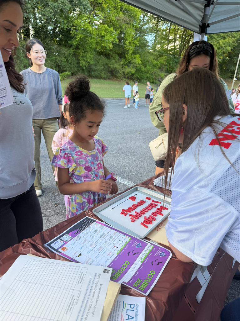 a student and her mother looking at magnetic letters with a kindergarten teacher at literacy night