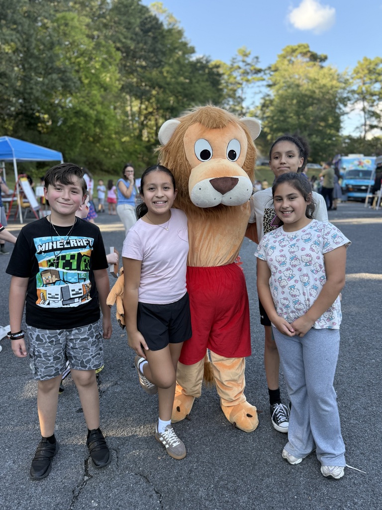 4 students posing with the Brookwood Lion mascot standing outside in a parking lot at Literacy Night!